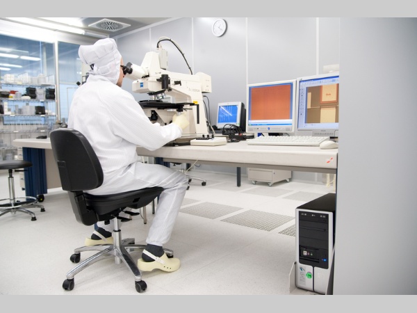 Touch Screen - Studii privind scrisul de mână al copiilor pe diferite tehnologii touchscreen: un bărbat într-un costum alb care lucrează la microscop